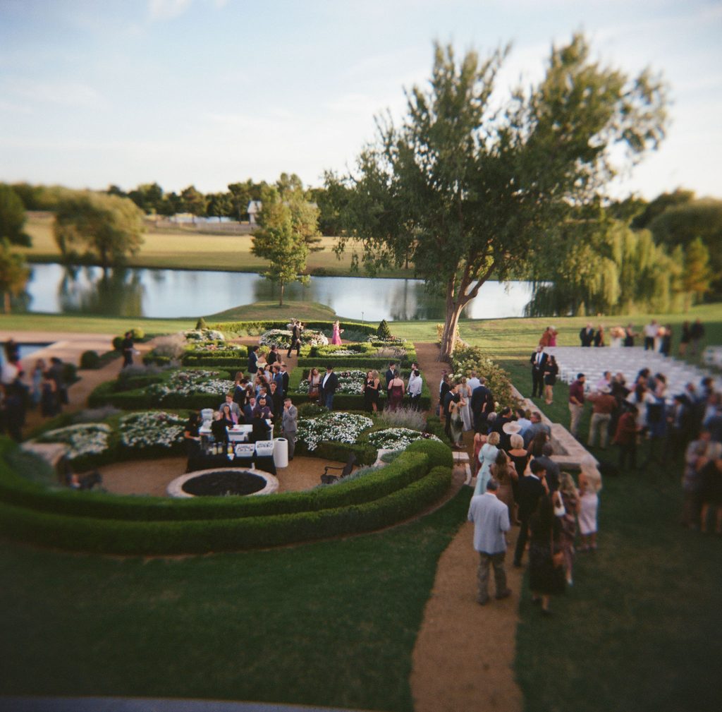Overhead wide shot of manicured garden walkways, hedges, and pond during outdoor cocktail hour at The Bower wedding venue in Edmond, OK.
