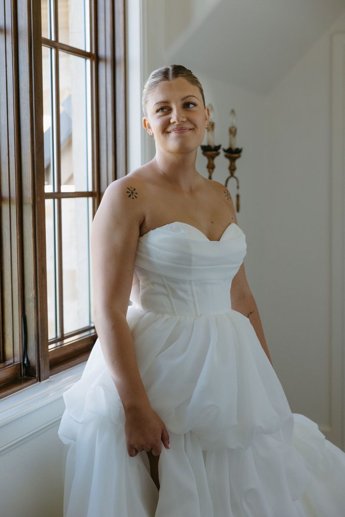 Detail shot of bride lifting layered tulle gown showing slit and leg indoors at The Bower in Edmond, Oklahoma.