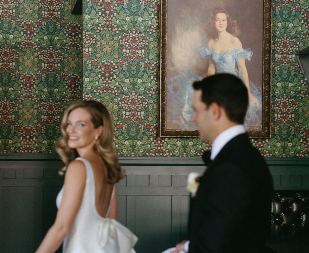 Bride over her shoulder looking back at groom in green wallpaper bridal suite at Oklahoma Hall of Fame.