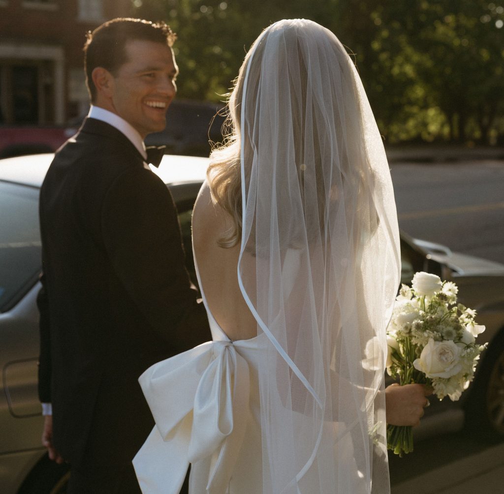 Backlit portrait of groom looking at bride wearing square-neck dress with pearl wedding veil at Oklahoma Hall of Fame.
