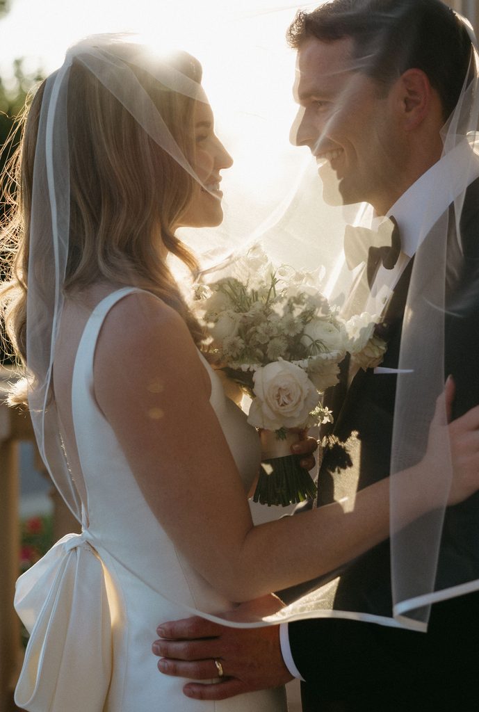 Backlight portrait of bride and groom in veil with bow detail on Neiman Marcus dress at Oklahoma Hall of Fame.