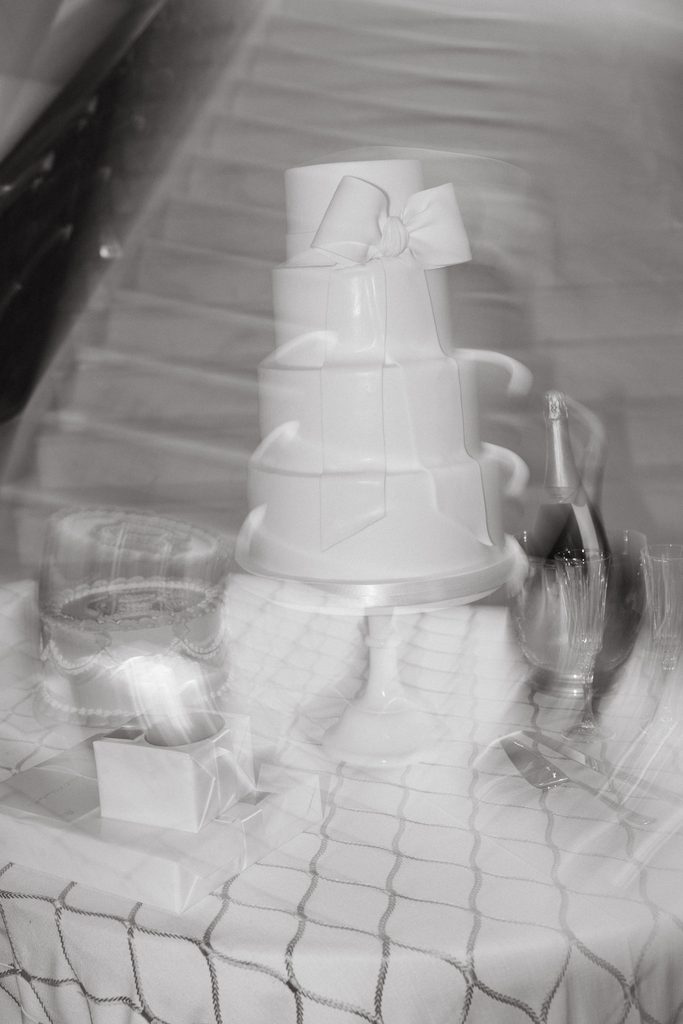 Black and white photo of multi-tiered wedding cake by Amy Cakes adorned with satin bow detail at Oklahoma Hall of Fame.